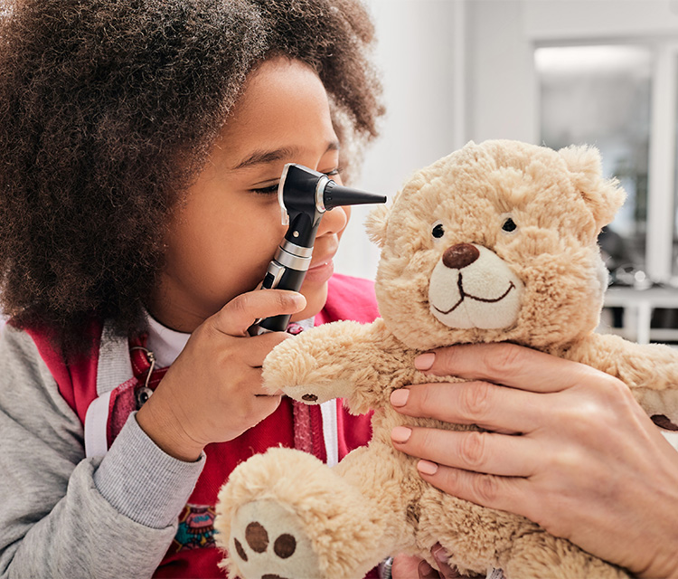 african-american-girl-plays-with-her-toy-bear-in-a-medical-game-using-an-otoscope