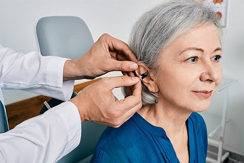 senior-woman-during-installation-hearing-aid-into-her-ear-by-her-audiologist-close