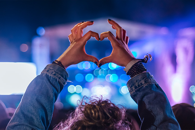 woman-making-heart-shape-with-hands-at-music-event